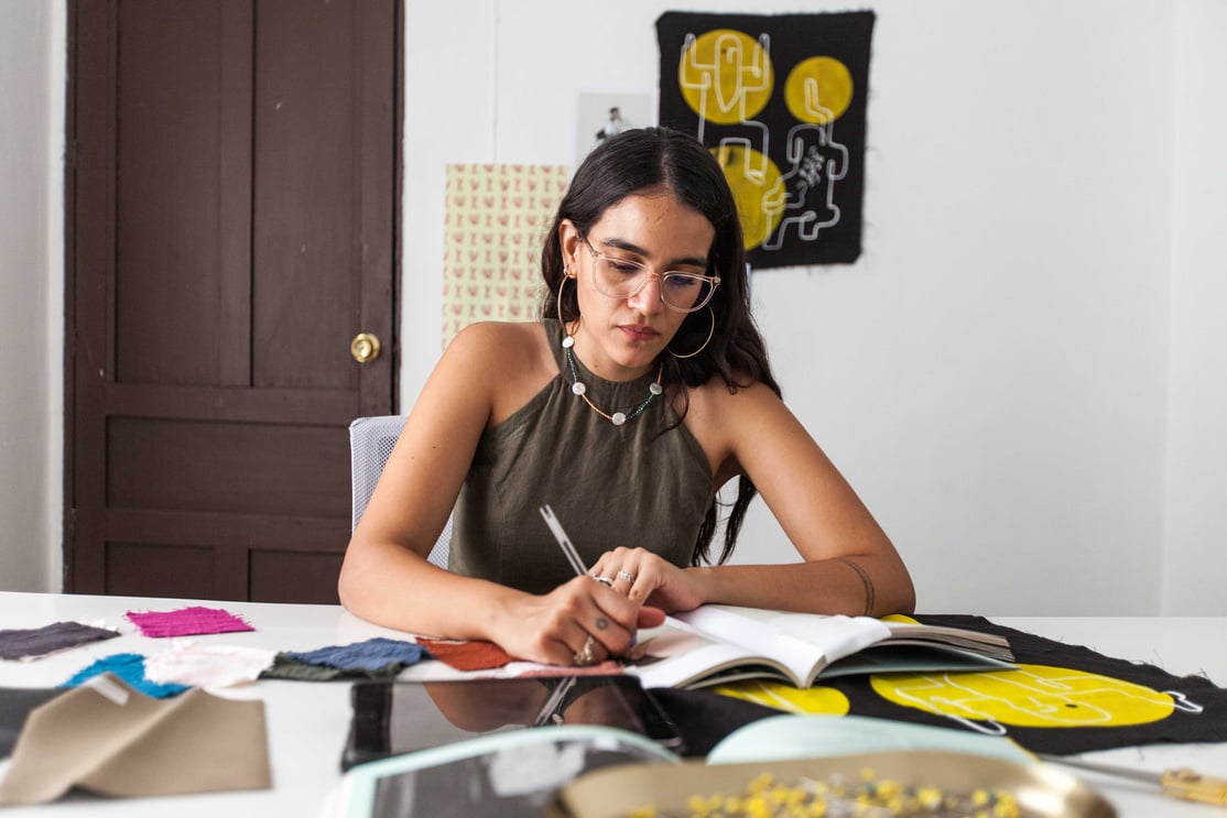 Photo of a Woman with Eyeglasses Writing on a Magazine